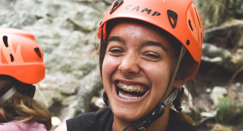 A person wearing an orange helmet smiles at the camera